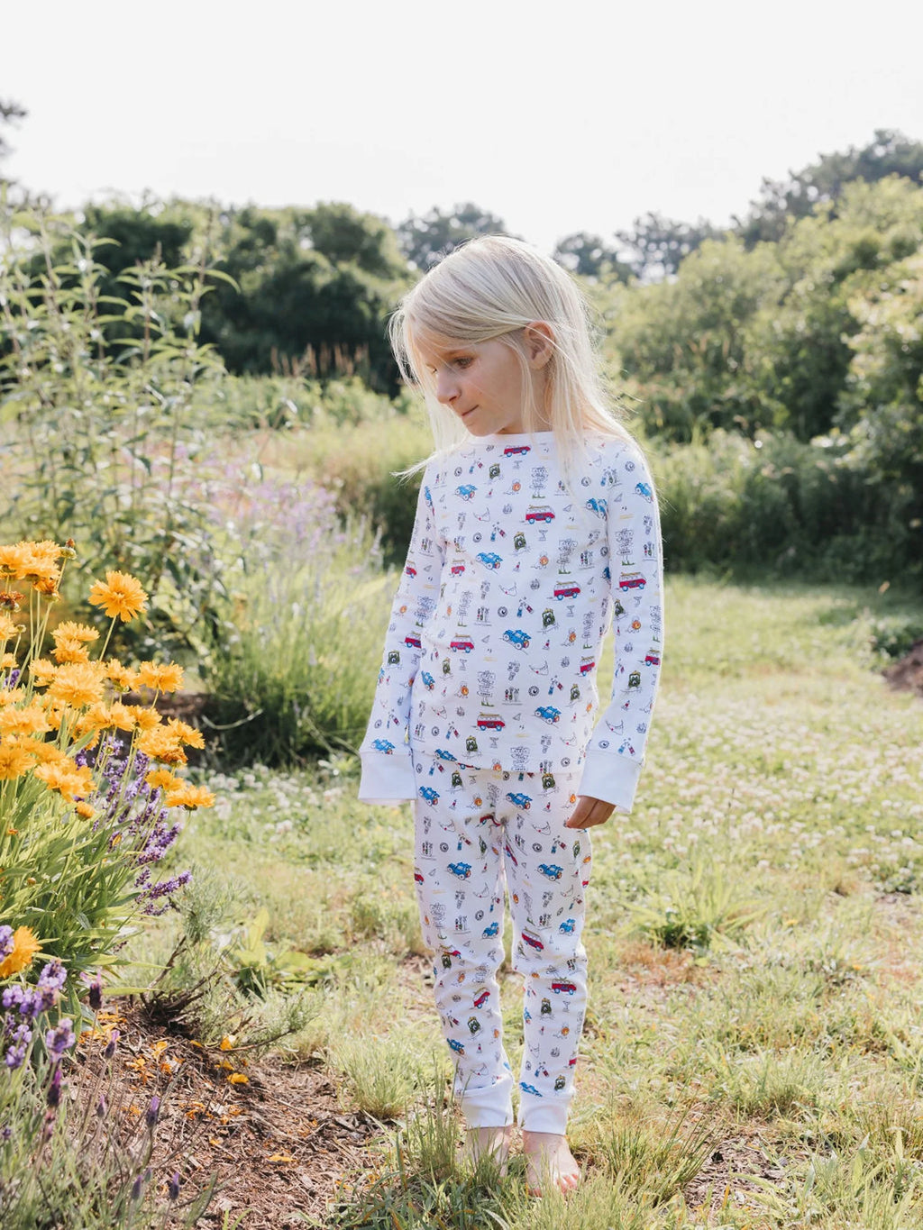 A little girl, wearing adorable Erica Wilson pajamas, captivates the moment with wide-eyed wonder while gazing at vibrant flowers